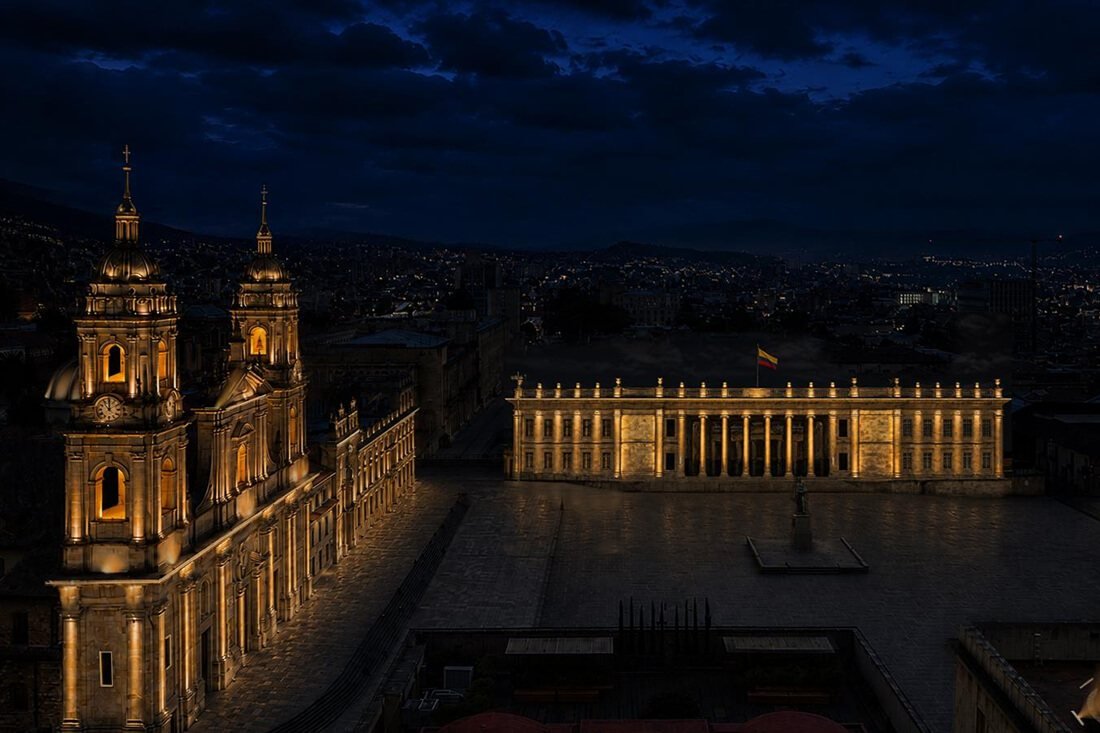 Vista aérea nocturna de la Plaza de Bolívar en Bogotá con edificios iluminados y el cielo oscuro