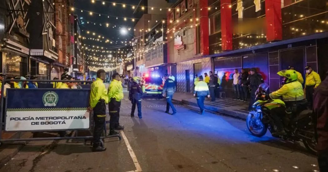 Agentes de la Policía Metropolitana de Bogotá patrullan una calle iluminada por la noche con luces azules y blancas
