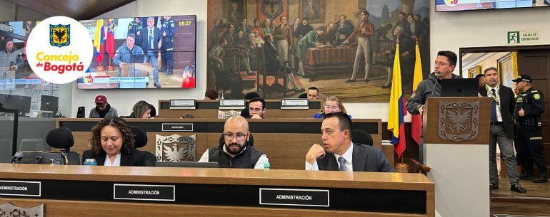 Sesión del Concejo de Bogotá con varios funcionarios sentados en una mesa de debate frente a una pantalla