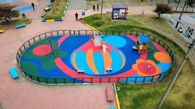 Vista aérea de un parque infantil con suelo de colores y estructuras de juego en Bogotá