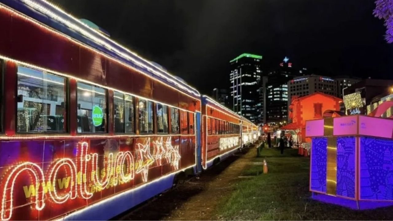 Tren decorado con luces navideñas y el texto 'Navidad' en un entorno urbano nocturno