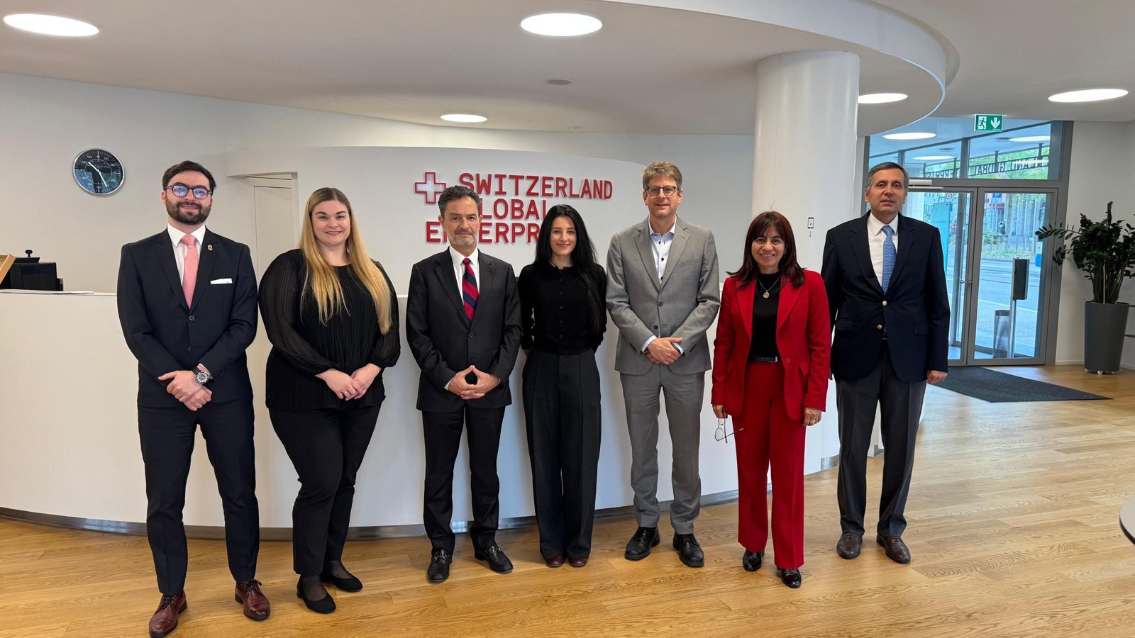 Siete personas posan juntas en el vestíbulo de una oficina con un logo de la empresa SIKA en la pared