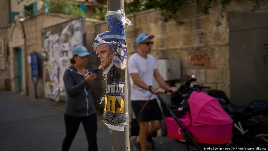 Una mujer mira su teléfono celular junto a un cartel publicitario en una calle de Israel