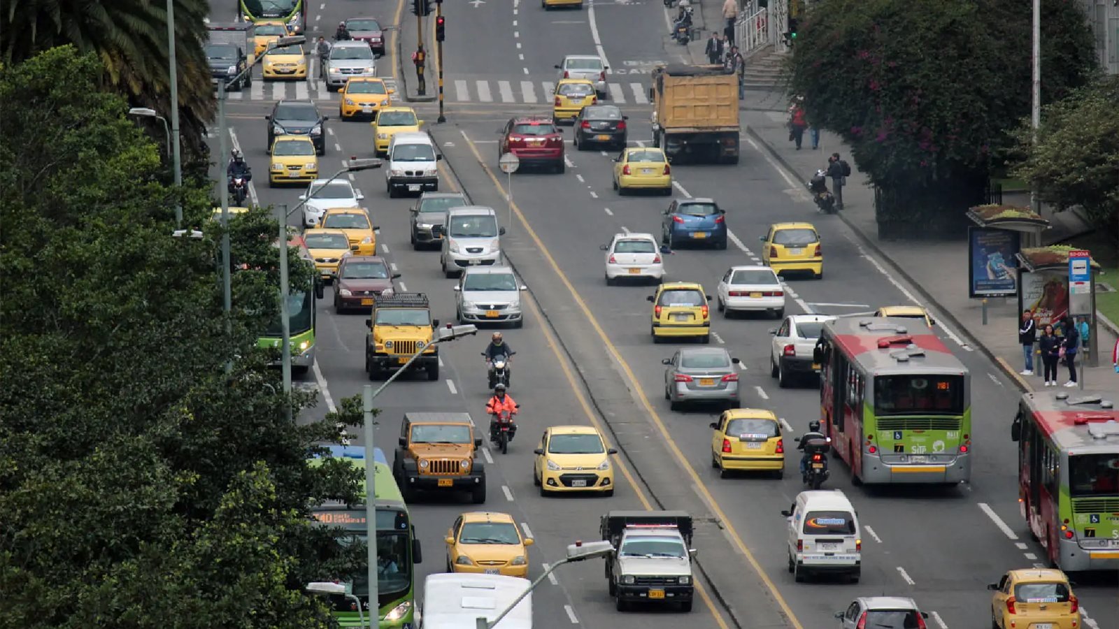 Vista aérea de una avenida en Bogotá con flujo de taxis amarillos, buses de TransMilenio y vehículos particulares