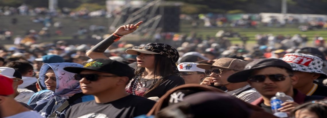 Multitud de personas con gorras y gafas de sol asisten a un festival al aire libre