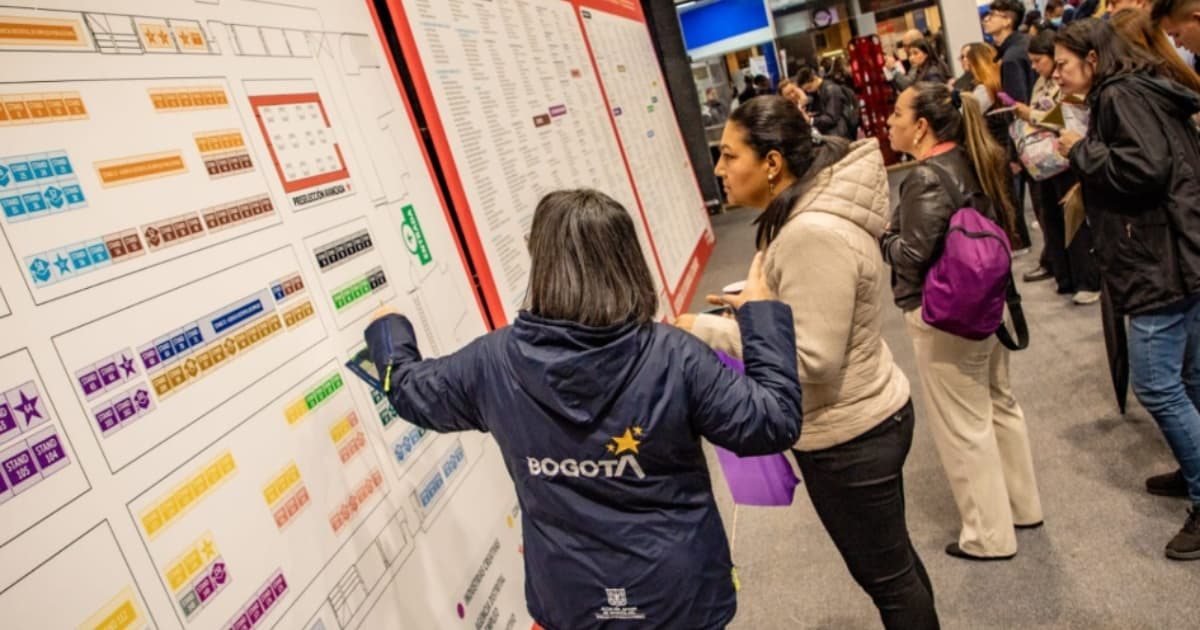 Personas revisan un gran mapa de rutas de transporte público en una estación de la ciudad de Bogotá.
